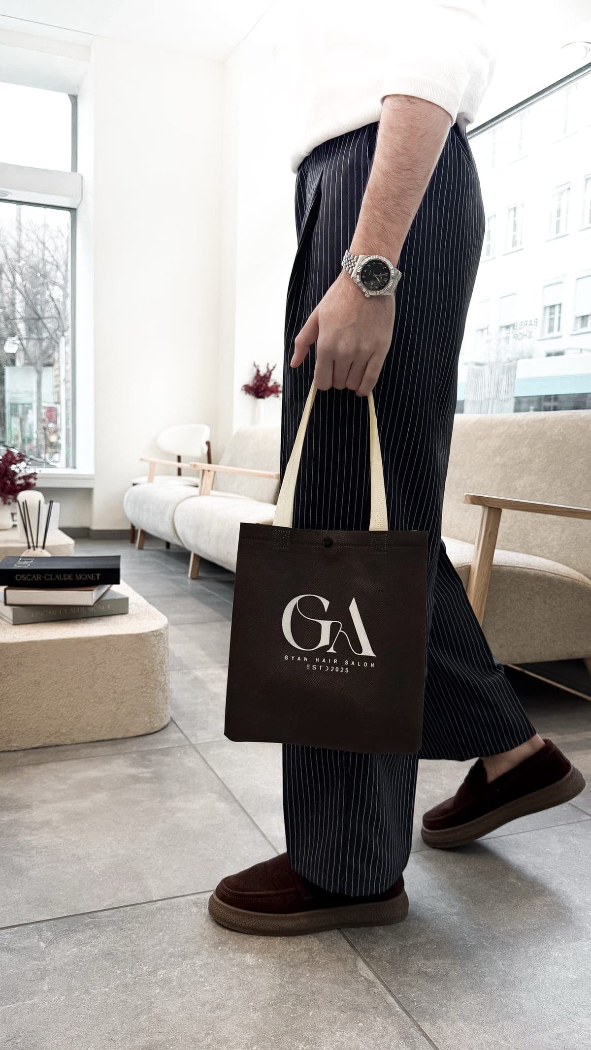 Kunde mit brauner GYAN-Tasche in der hellen Lounge des Salons